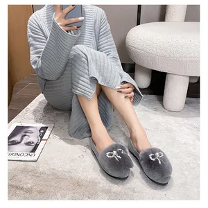 Detailed view of gray faux fur loafers with pearl and rhinestone bow on model feet