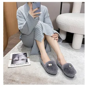 Detailed close-up of grey faux fur loafers with gold metal buckle on a cozy rug