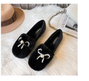 Detail of plush black loafers featuring a pearl bow and warm fleece lining
