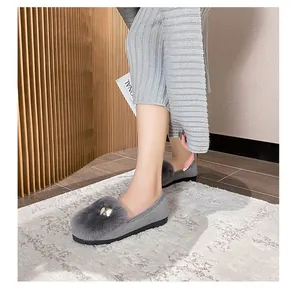 Detail of gray suede loafers with plush fur trim and decorative bead on a stylish model