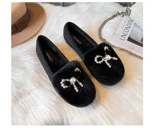 Macro detail of plush faux fur texture and elegant pearl rhinestone bow on black loafer