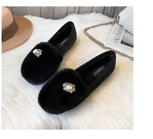 Detail of black faux fur loafers with pearl and rhinestone embellishments on soft carpet