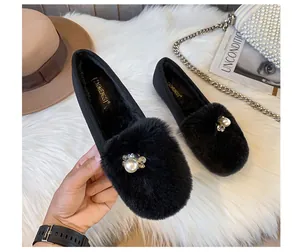 Detail of black faux fur loafers with pearl and rhinestone floral decor on plush rug
