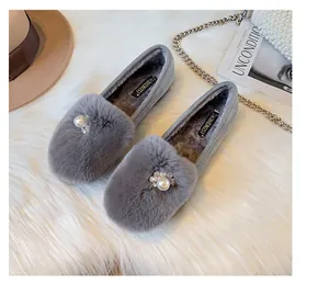 Detail of gray faux fur loafers featuring a large pearl accent and plush lining