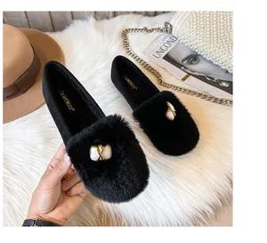 Detail of warm black faux fur loafers with decorative pearls and golden metal buckles