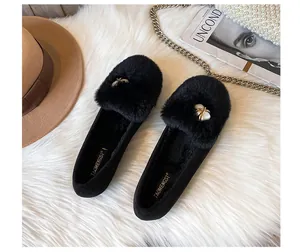 Close-up of black plush loafers with gold metal buckle and white pearl detail