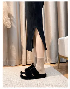 Detail view of black faux fur platform slide sandals styled with socks and knit skirt