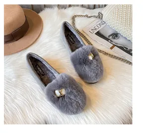 Detail of grey plush loafer with pearl buckle and warm lining on white soft carpet