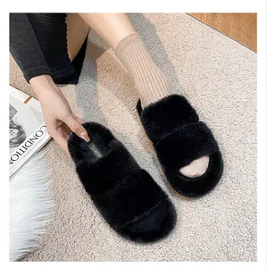 Top view of plush black faux fur slippers with double straps on soft grey carpet