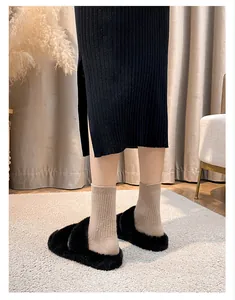 Close-up of black fuzzy platform slippers with plush crisscross straps and thick sole