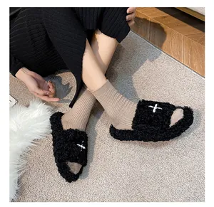 Detail of black fuzzy slide slippers with white star embroidery and thick plush soles