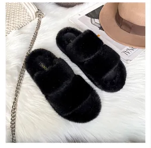 Detail of warm black faux fur slide slippers with soft plush texture and brand label