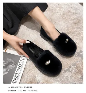 Detail von schwarzen Kunstfell-Loafers mit Perlen- und Strassbesatz auf beige Teppich