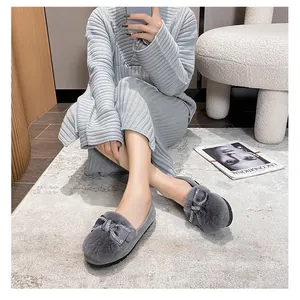 Dettaglio di scarpe slip-on in peluche grigio con fiocco di strass e suola in gomma