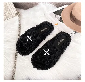 Flat faux fur slide slippers in black with white cross X design on soft plush carpet