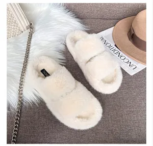 Top view of plush cream faux fur slide slippers with double straps on a cozy carpet