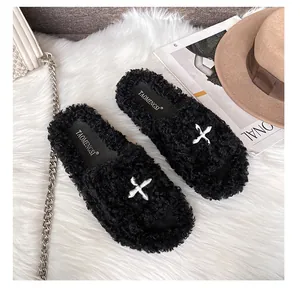 Flat lay of black plush platform slippers on a white rug with stylish fashion accessories