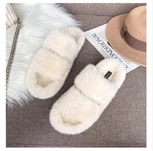 Flat lay view of cream faux fur double-strap slippers with a stylish handbag and hat