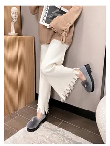 Seitenansicht grauer Pelz-Loafer mit Perlenakzenten und dicker schwarzer Sohle am Modell