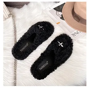 Macro detail of plush faux fur texture and silver cross metal buckle on black slippers