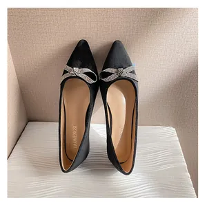 Draufsicht auf schwarze spitze Wildleder-Ballerinas mit einer funkelnden Strass-Schleife
