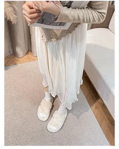 Cozy white faux fur slides styled with white socks and a flowing skirt in a home setting