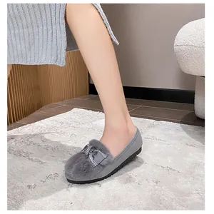 Dettaglio di scarpe slip-on in peluche grigio con fiocco di strass e suola spessa in gomma