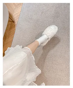 Detailed close-up of white plush slippers with cross star flower and fleecy texture