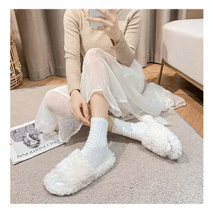 Close-up of white fluffy platform slide slippers with soft plush texture on grey rug