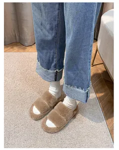 Detail of plush brown double-strap slippers with warm faux fur and flat soles on carpet