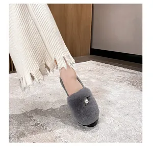 Detaillierte Nahaufnahme grauer Kunstpelz-Loafer mit einer weißen Perle als Verzierung