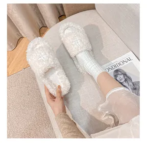 Detail view of cream plush slide sandals with cross embroidery and thick faux fur lining
