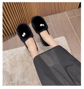 Nahaufnahme der schwarzen flachen Winterschuhe mit weichem Kunstfell und goldener Schnalle