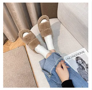 Close-up of plush camel double-strap flat slide slippers worn with cozy white knit socks