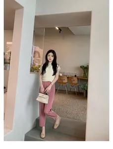 Elegante outfit estivo con top in maglia beige, pantaloni rosa e ballerine con fiocco in una hall
