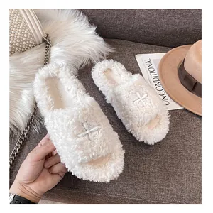 Close-up of off-white plush open-toe slippers with decorative white cross patches