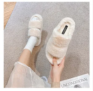Detail of cream plush flat slippers showing thick faux fur texture and dual strap design
