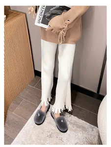Nahaufnahme von Strickhose mit weitem Bein, Fransensaum und Plüschschuhen aus Kunstpelz