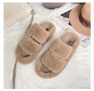 Top view of plush tan faux fur double-strap platform slippers on a soft white rug