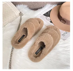 Flat faux fur slippers in light brown shown on a soft rug with fashion accessories