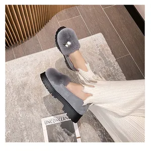 Detailaufnahme grauer Plüsch-Plateau-Loafer mit Perlenschnalle auf einem strukturierten Teppich