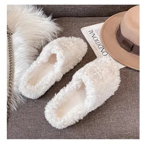 Dettaglio di pantofole in peluche bianco con trama in pile e cucitura a croce