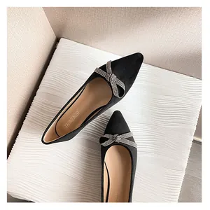 Eleganti ballerine nere a punta con fiocco di strass su sfondo bianco ondulato