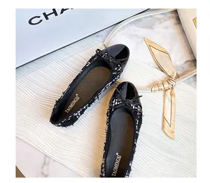 Detail view of tweed ballet flats with black patent leather toe and bow decoration