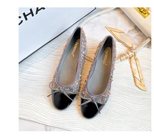 Close-up of grey tweed ballet flats featuring black patent toe and delicate bow detail