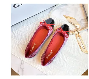 Close-up of pink tweed ballet flats with black patent toe cap and red bow detail