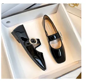 Dettaglio di scarpe Mary Jane in vernice nera con punta quadrata e fibbia con perle