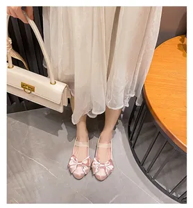 Ballerines en satin rose avec gros-grain rose avec grand nœud et bride élastique portées aux pieds