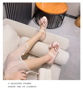 Détail de ballerines en satin rose avec grand nœud et bride élastique dans un salon