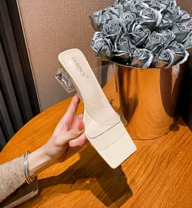 Detail einer Pantolette mit eckiger Zehenpartie, transparentem Blockabsatz und PVC-Riemen